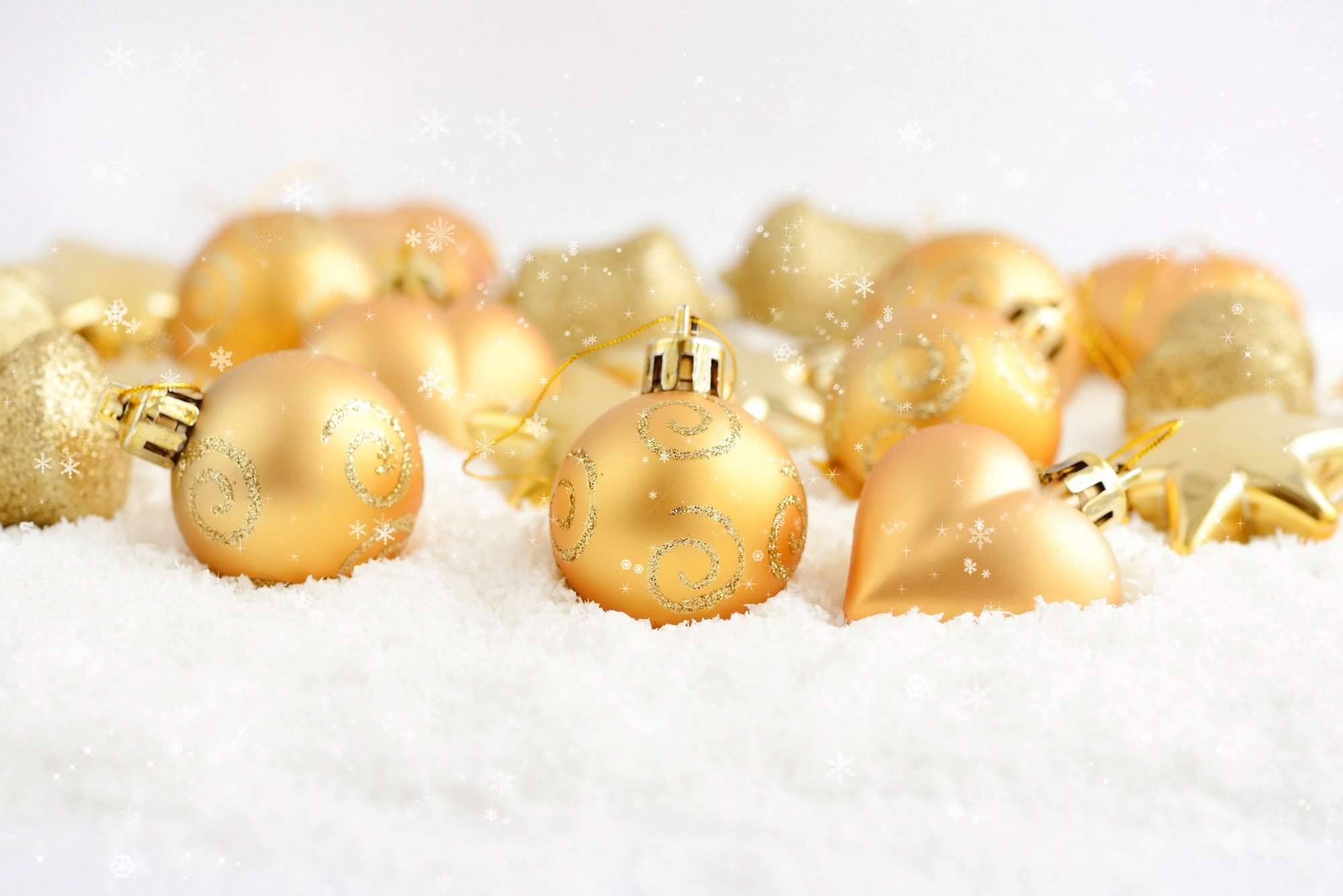 Christmas gold ornaments on the snow. Festive Christmas backgrou